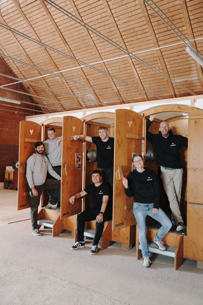 Das Kompotoi-Team posiert gemeinsam in einer Halle vor mehreren Holz-Toilettenkabinen – Symbol für nachhaltige Sanitärlösungen im Tourismus.