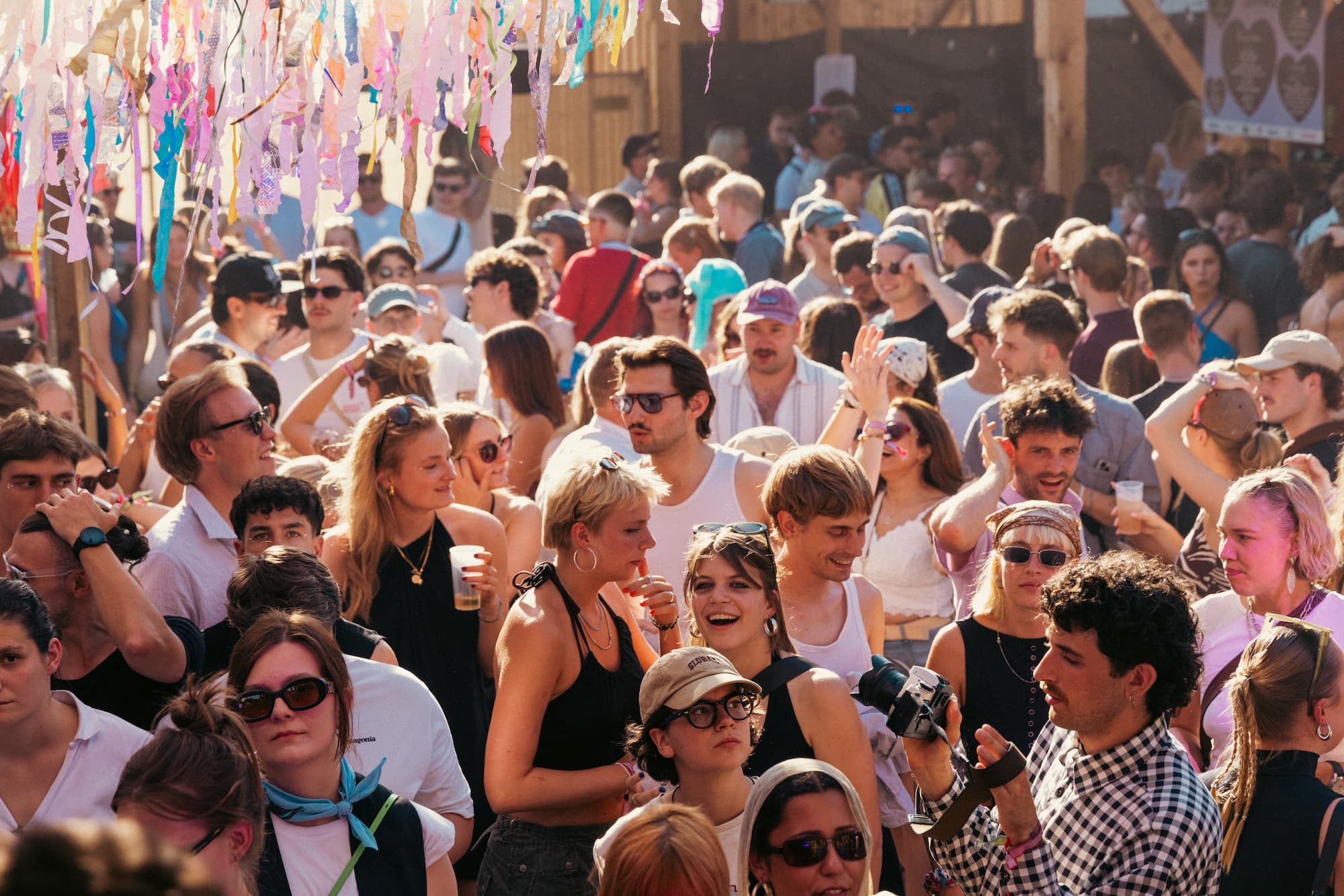 Tanzende Besucher:innen beim Trägertalfestival links oben hängen bunte Dekoschlangen ins Bild